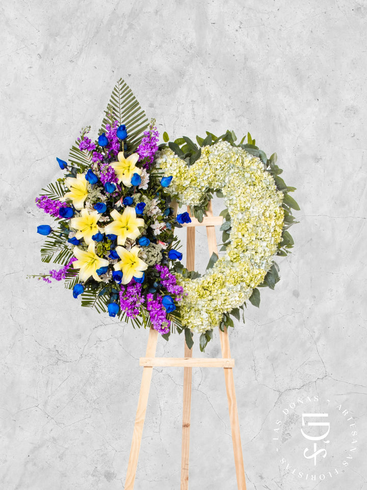 Corona de Corazón con Hortensias, Rosas Azules y Liliums arreglo de condolencias con 24 rosas azules